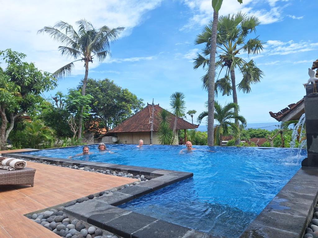 una piscina en un complejo con gente dentro en Frangipani Inn & Restaurant, en Seraya