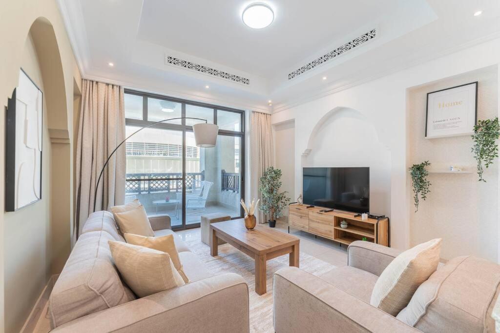 ein Wohnzimmer mit einem Sofa und einem TV in der Unterkunft Traditional 2 Bedroom with Dubai Fountain View in Dubai