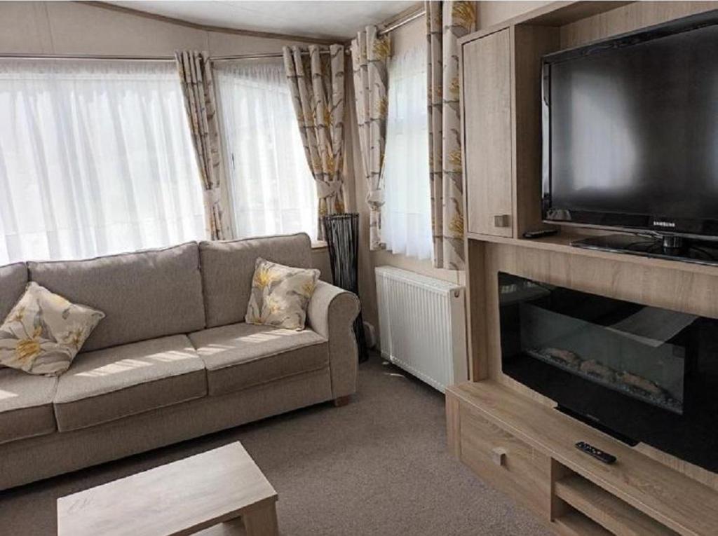 a living room with a couch and a flat screen tv at Lovely Caravan At Hoburne Bashley, New Forest District! Ref 97166s in New Milton