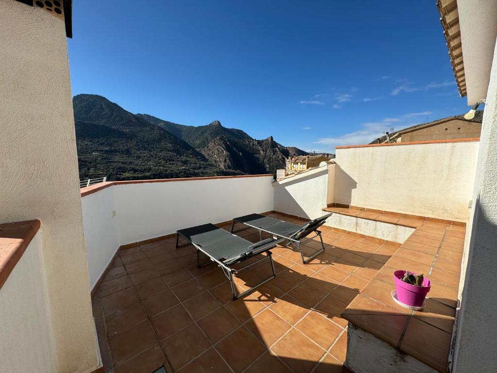 a balcony with a table and chairs on a roof at Casa a la Vera de la Sierra in Güéjar-Sierra