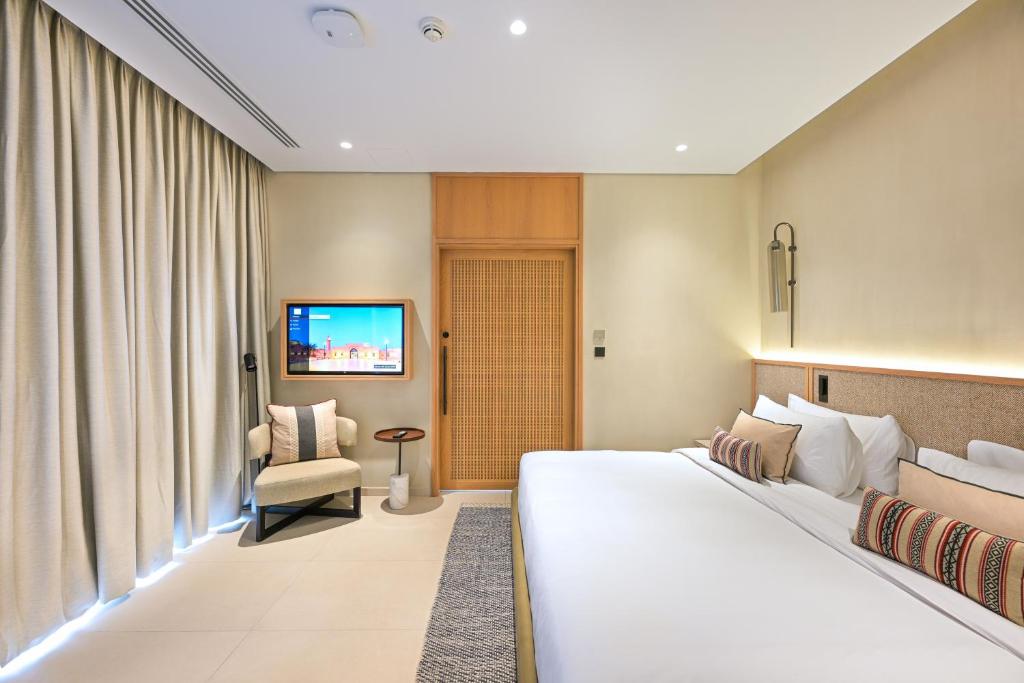 um quarto de hotel com uma cama e uma cadeira em Al Badayer Retreat by Sharjah Collection em Sharjah