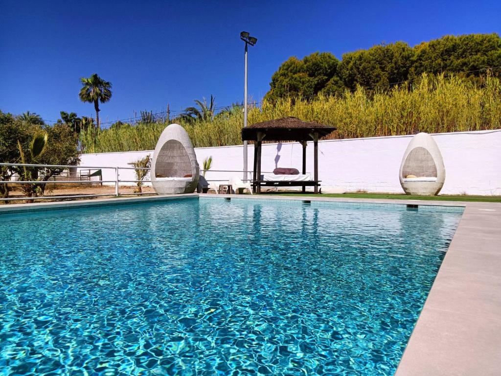 una piscina con cenador y agua azul en 30 people, pool, disco,10 min beach, en Alicante