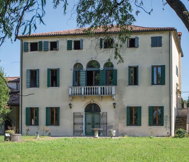 een groot wit huis met groene luiken bij enJoy Home - Villa Ca' Dura in Ronchi di Campanile