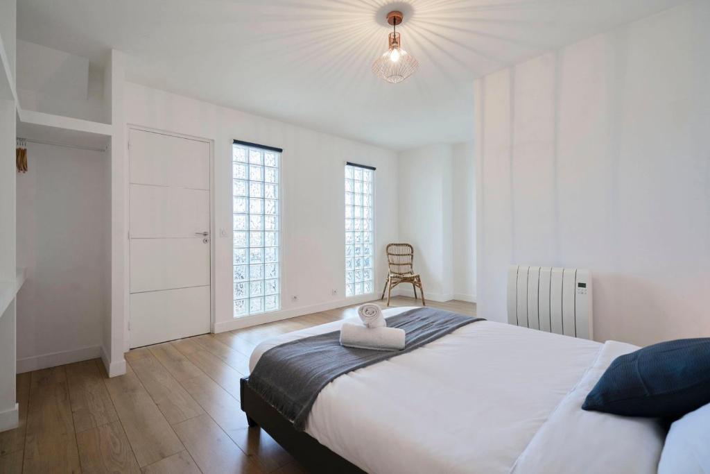 a white bedroom with a large bed and windows at Loft en duplex atypique 4ch + parking in Tourcoing