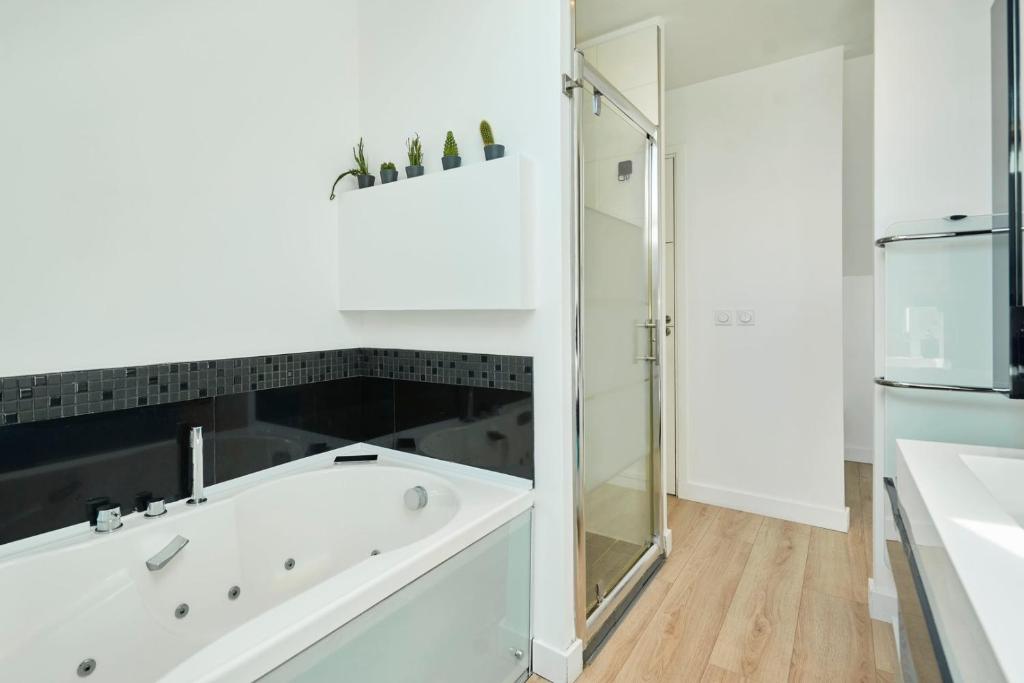 a white bathroom with a tub and a shower at Loft en duplex atypique 4ch + parking in Tourcoing
