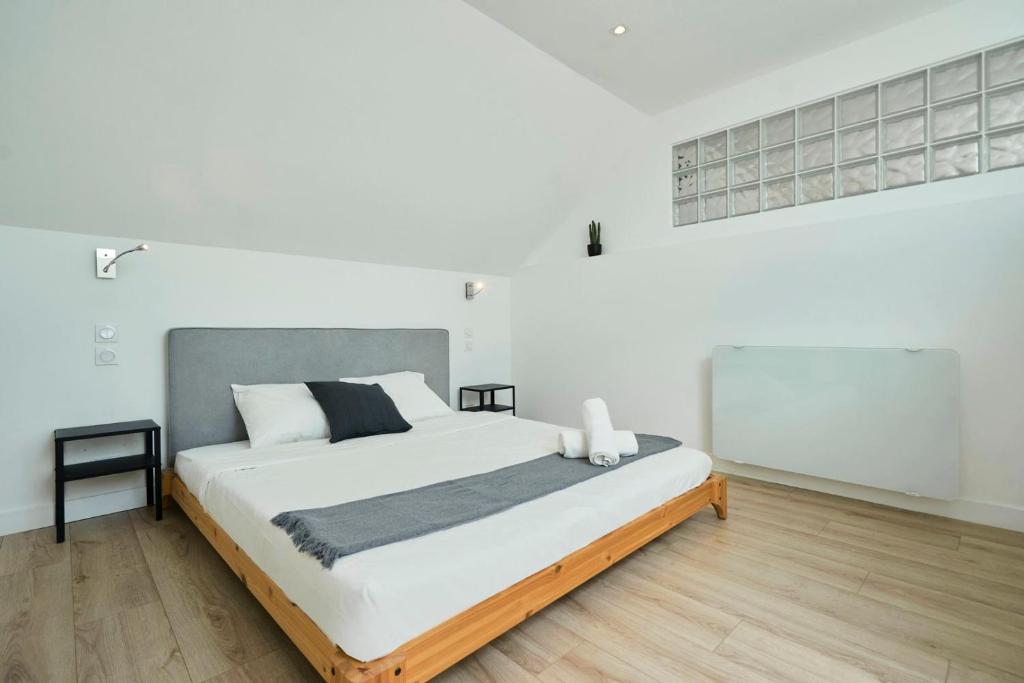 a bedroom with a large bed in a white room at Loft en duplex atypique 4ch + parking in Tourcoing