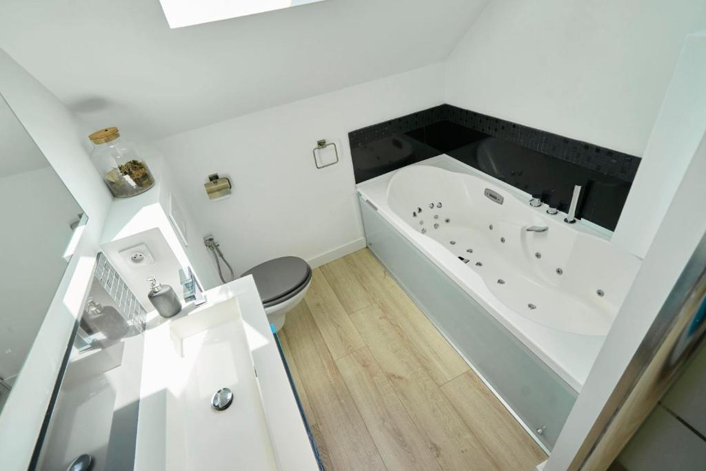 a white bathroom with a tub and a toilet at Loft en duplex atypique 4ch + parking in Tourcoing