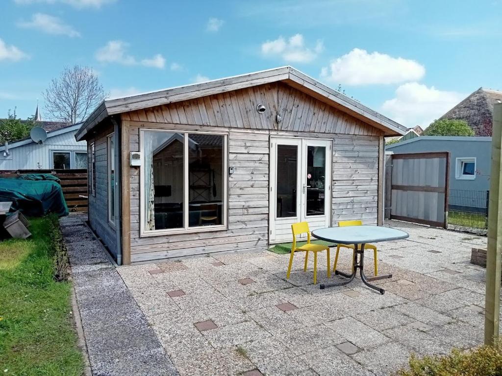 a small shed with a table and chairs in a yard at tiny house nabij de kust in Dirkshorn