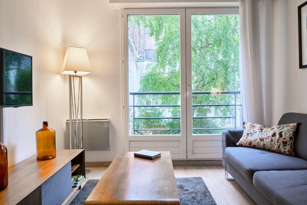 sala de estar con sofá y ventana grande en Lille Centre - Superb bright apartment parking en Lille