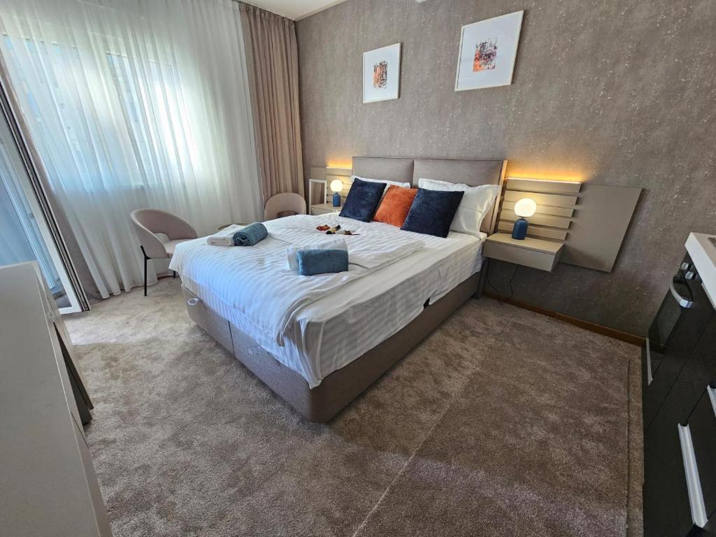 um quarto com uma cama grande com almofadas azuis e laranja em AGAPE Apartment em Podgorica