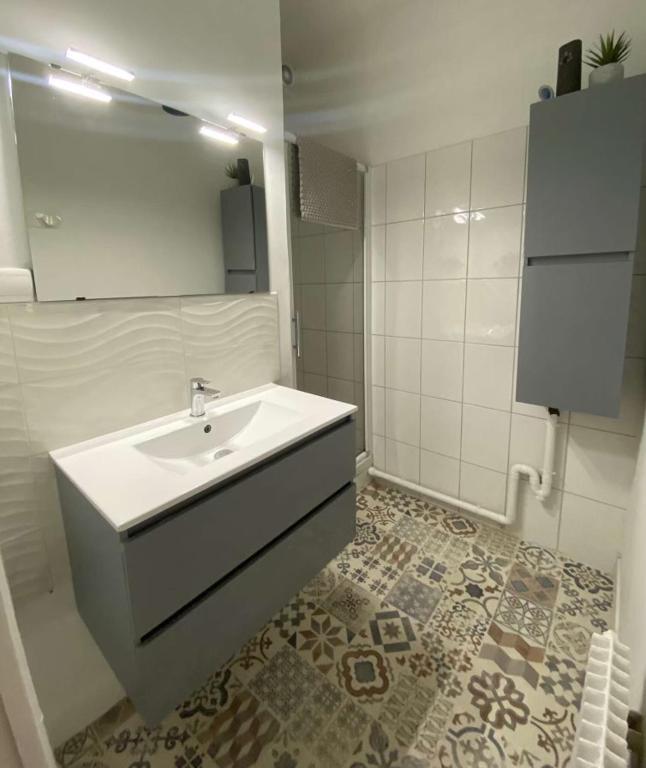 a white bathroom with a sink and a mirror at Maisonnette cocooning in Nogent-le-Rotrou