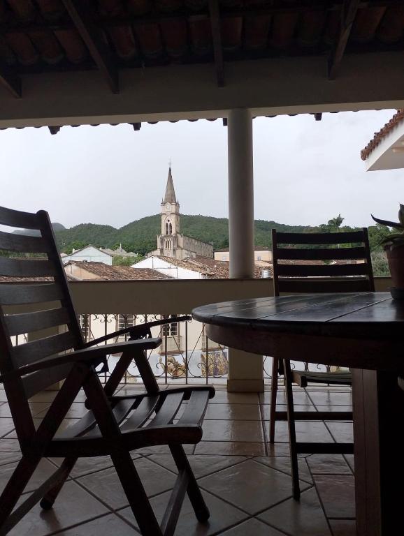 a table and chairs on a balcony with a church at Casa da Ponte Hotel in Goiás