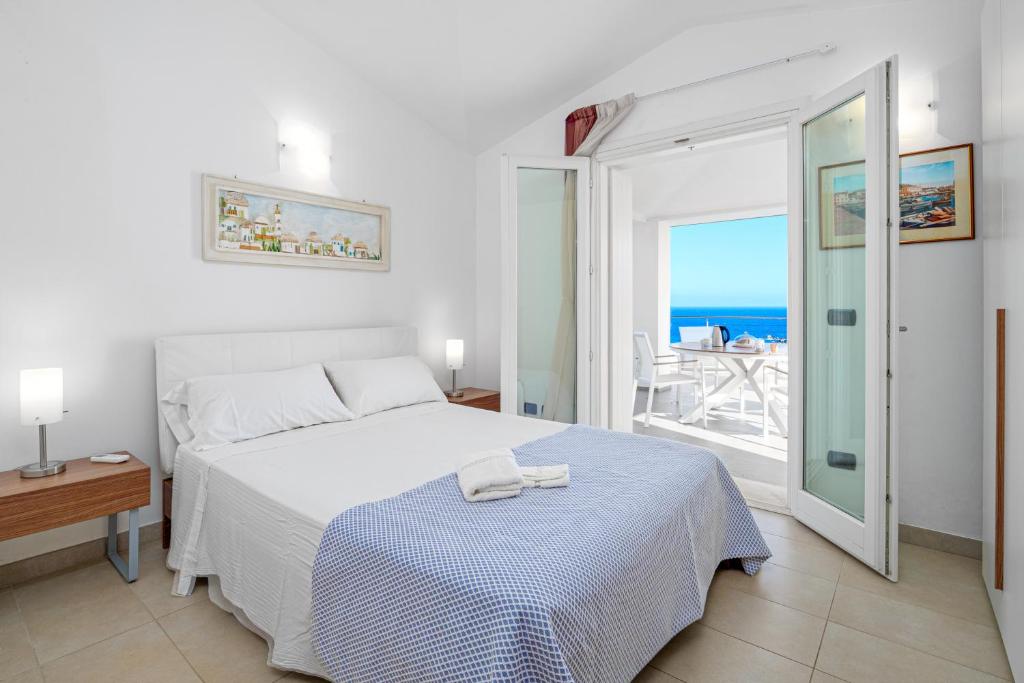 1 dormitorio con cama y vistas al océano en Villa Marconi Apartment 12 attico, en Golfo Aranci