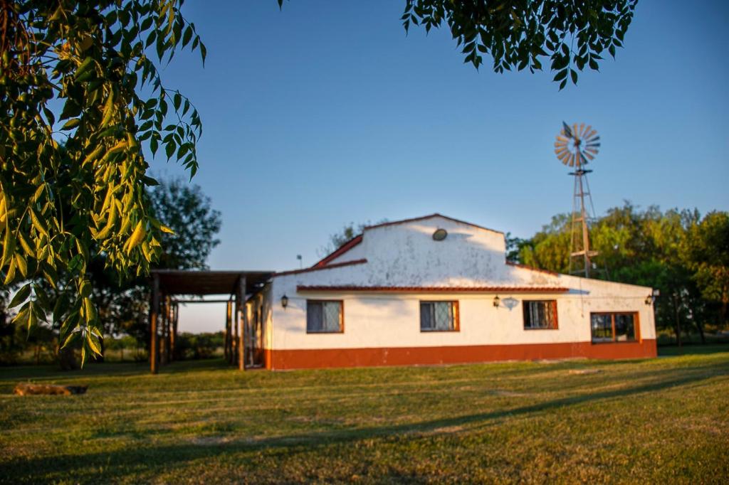 una casa en un campo con un molino de viento al fondo en Yellow Cardinal Lodge, en Curuzú Cuatiá