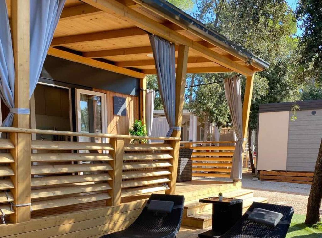 een terras met een houten pergola en stoelen bij Oliva Mobile Home in Biograd na Moru