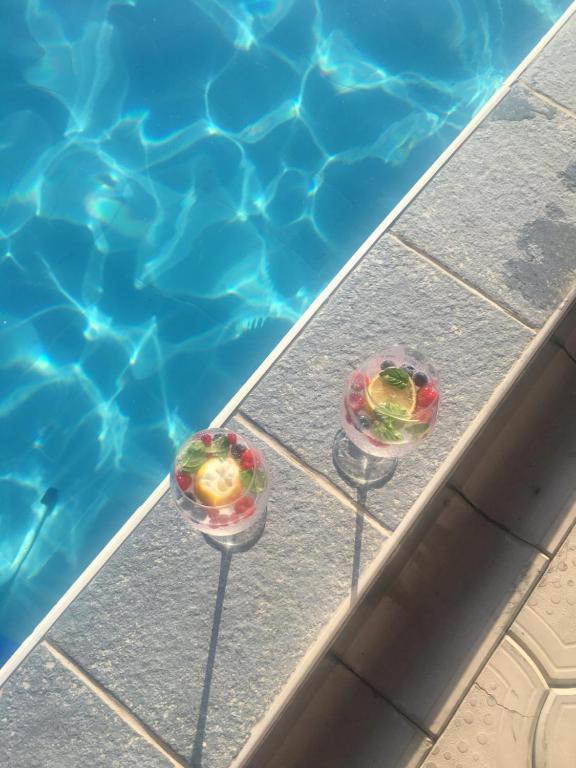 two glasses of fruit sitting next to a swimming pool at Smeštaj "Lapčević" in Soko Banja