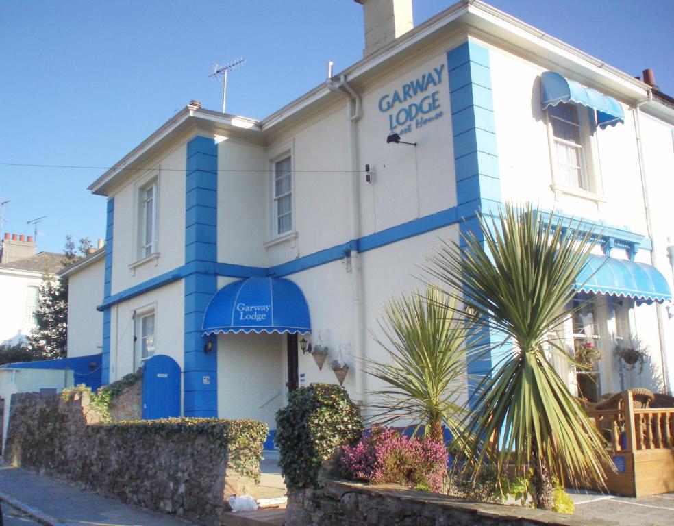 a white and blue building with a palm tree in front at Garway Lodge Guest House in Torquay