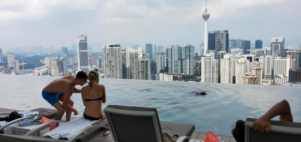 deux hommes debout au bord d'une piscine dans l'établissement Bunga Suite at Lucentia BBCC, à Kuala Lumpur