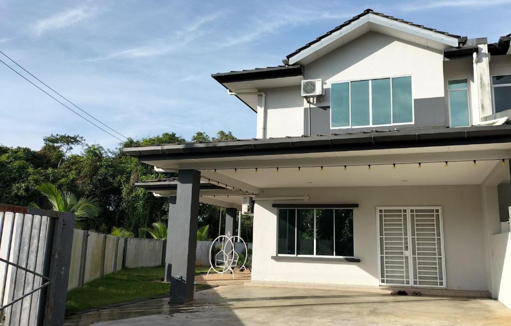 una casa blanca con una puerta y una valla en Homestay @Seri Sindang Guesthouse en Kota Samarahan