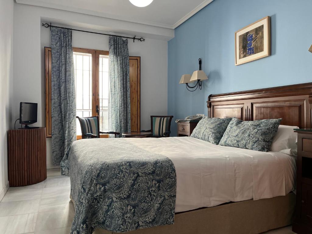 a bedroom with a large bed with blue walls at Hotel Maestre in Córdoba