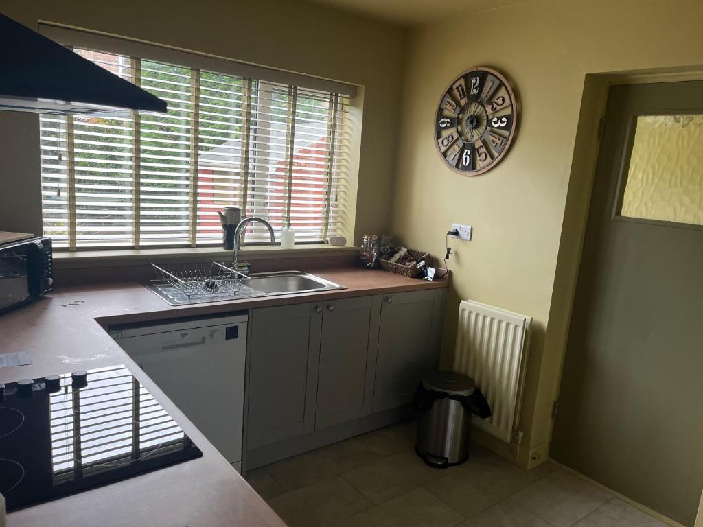 a kitchen with a sink and a clock on the wall at Woodstock by Spires Accommodation a uniquely Retro place to stay near Wolverhampton in Codsall