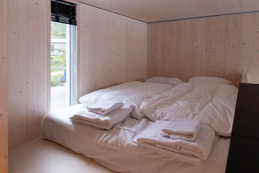 un letto bianco con asciugamani in una stanza di Fantastic mini-house on the waterfront a Ramberg