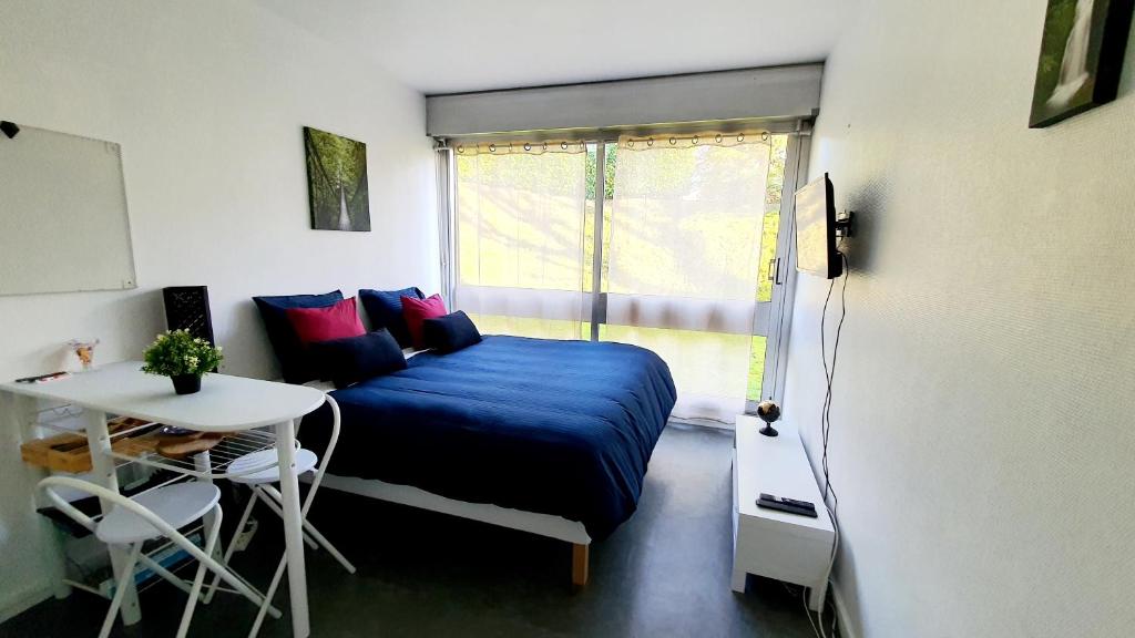 1 dormitorio con cama, mesa y ventana en Charme et bien-être à 10 minutes du Château de Versailles, en Le Chesnay