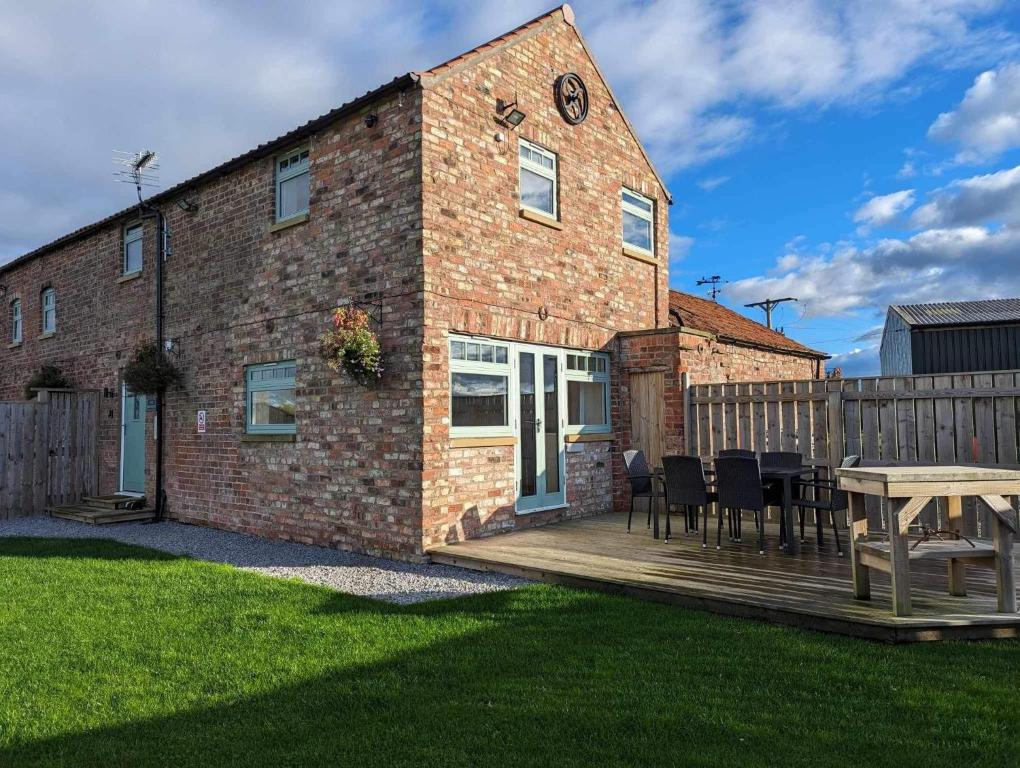 a brick house with a deck and a table at The Granary, quiet countryside location near York in Wilberfoss