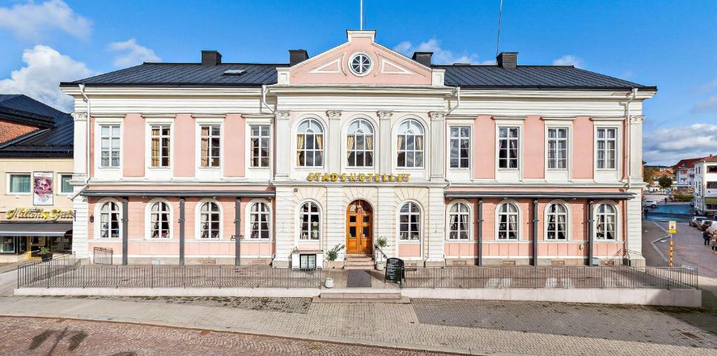 a large pink and white building on a street at Vimmerby Stadshotell, WorldHotels Crafted in Vimmerby