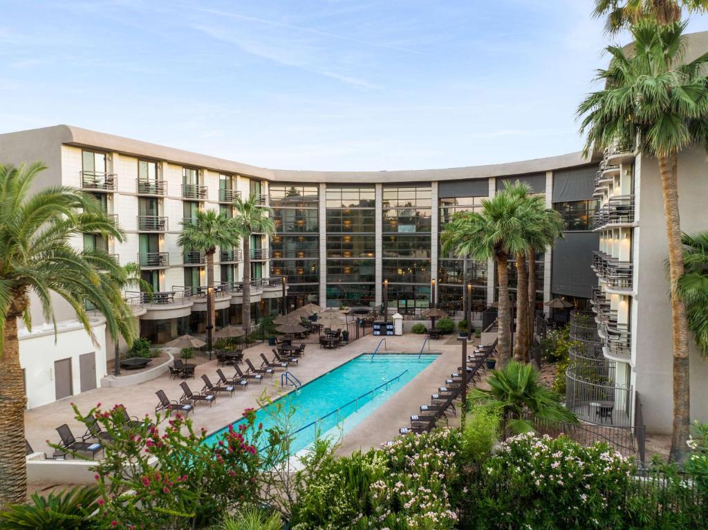 an exterior view of a hotel with a pool and palm trees at Embassy Suites by Hilton Phoenix Biltmore in Phoenix