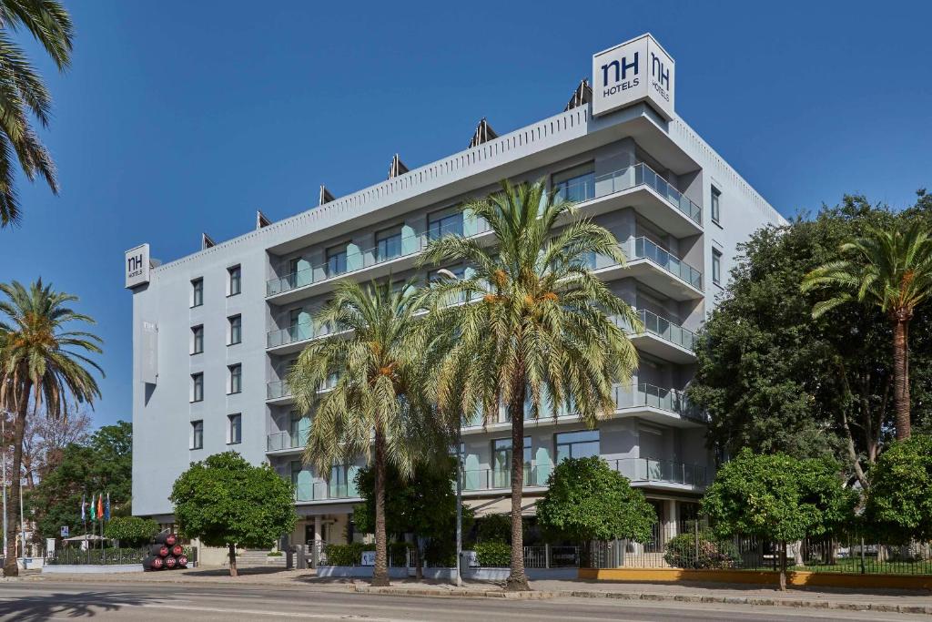 un edificio blanco con palmeras delante en NH Avenida Jerez en Jerez de la Frontera