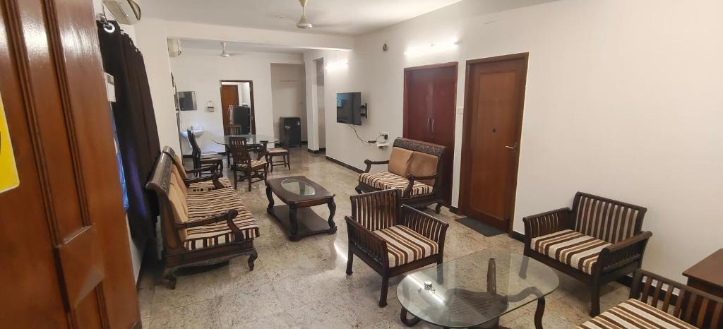 a living room with a bunch of chairs and a table at HACIENDA APARTMENT in Chennai