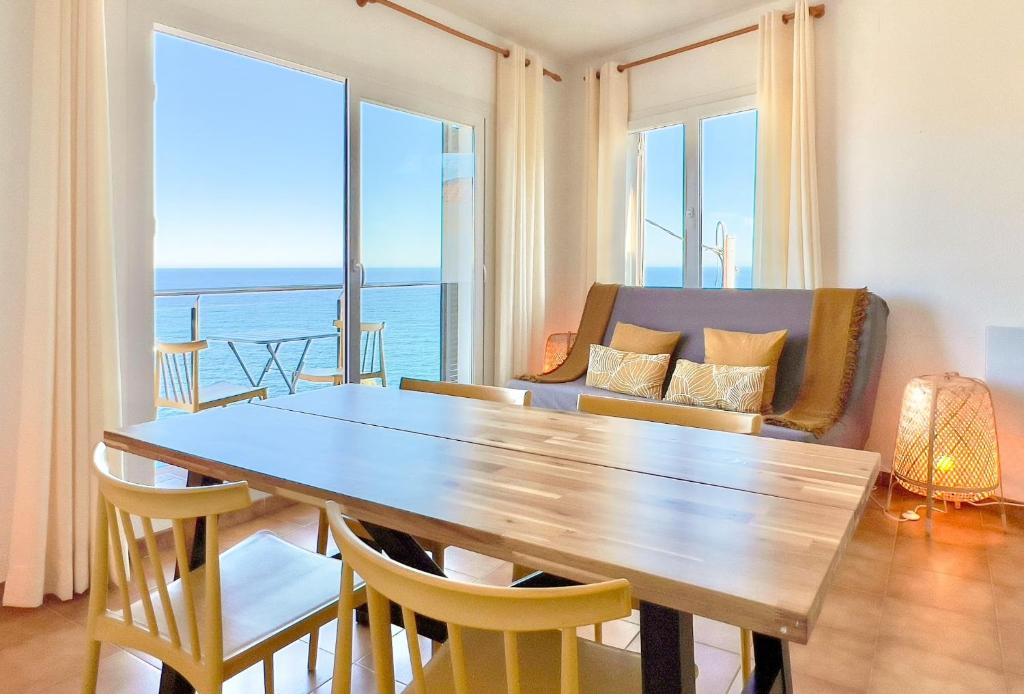 a dining room with a table and chairs with a view of the ocean at Majordoms - Apartment Cau del Llop, Llança in Llança