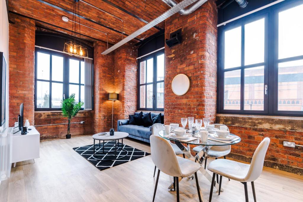 a living room with a brick wall and a table and chairs at Meadow Mill by Staycay in Stockport