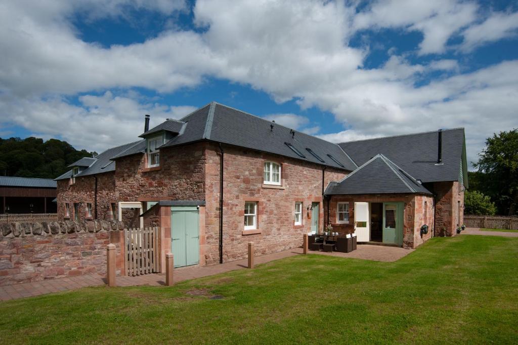 a large brick house with a black roof at Dryburgh Steading Three in Saint Boswells