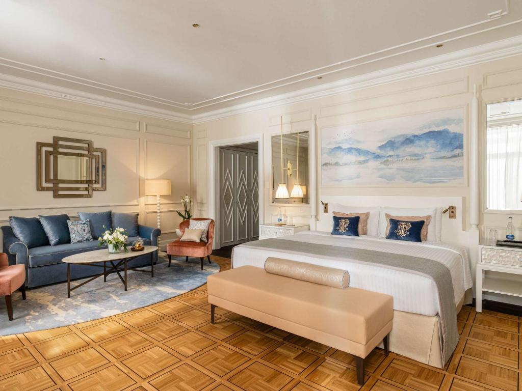 a bedroom with a king sized bed and a couch at Fairmont Le Montreux Palace in Montreux