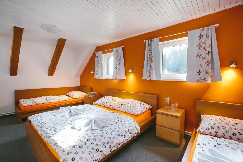 2 camas en una habitación con paredes y ventanas de color naranja en Chata Ťapka, en Dolní Malá Úpa