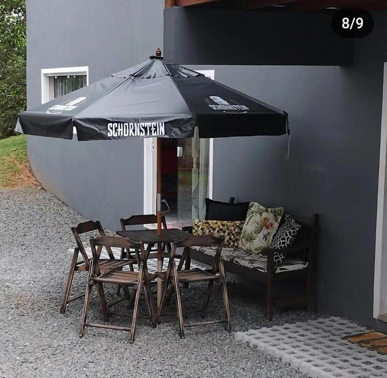 a table and chairs with an umbrella and a couch at Hostel SIL CARDOSO in Blumenau