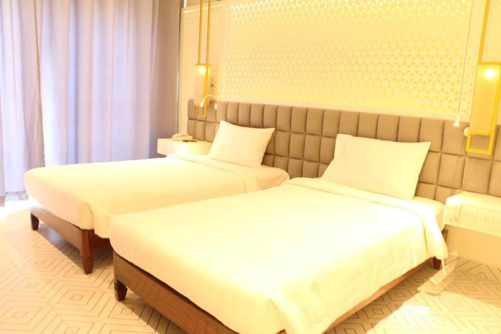 two beds in a hotel room with white sheets at Hengly Mohasambath Hotel & Spa in Phumĭ Kruŏs