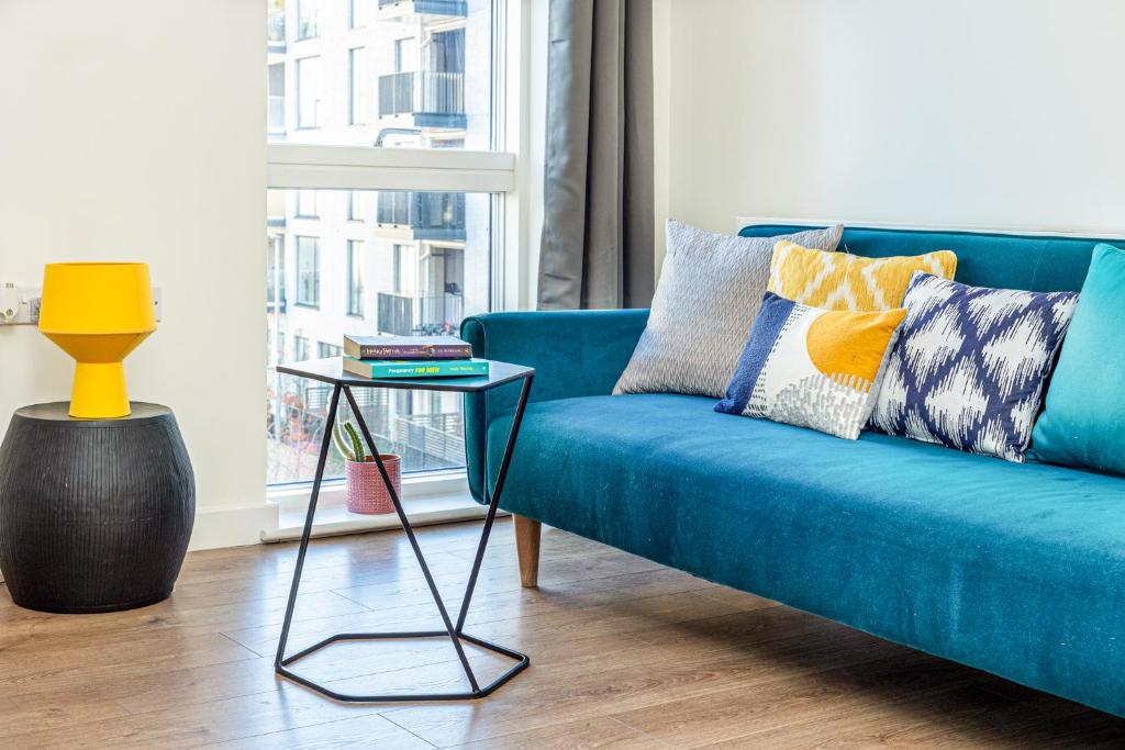 倫敦的住宿－Modern New 2BR flat wBalcony in peaceful Brixton，客厅配有一张蓝色的沙发,配有一张桌子
