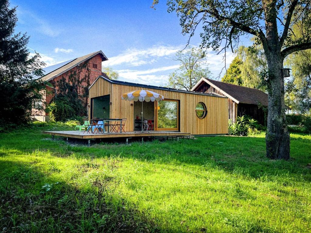 a house with a deck in the middle of a yard at Die Klingerei - Tiny House Wiese in Pettighofen