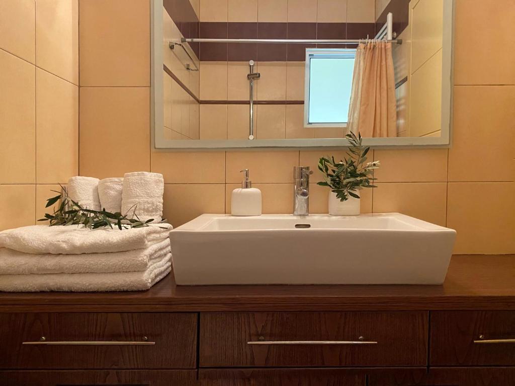W łazience znajduje się umywalka, lustro i ręczniki. w obiekcie Aegina Sea View Villa w mieście Aegenitissa