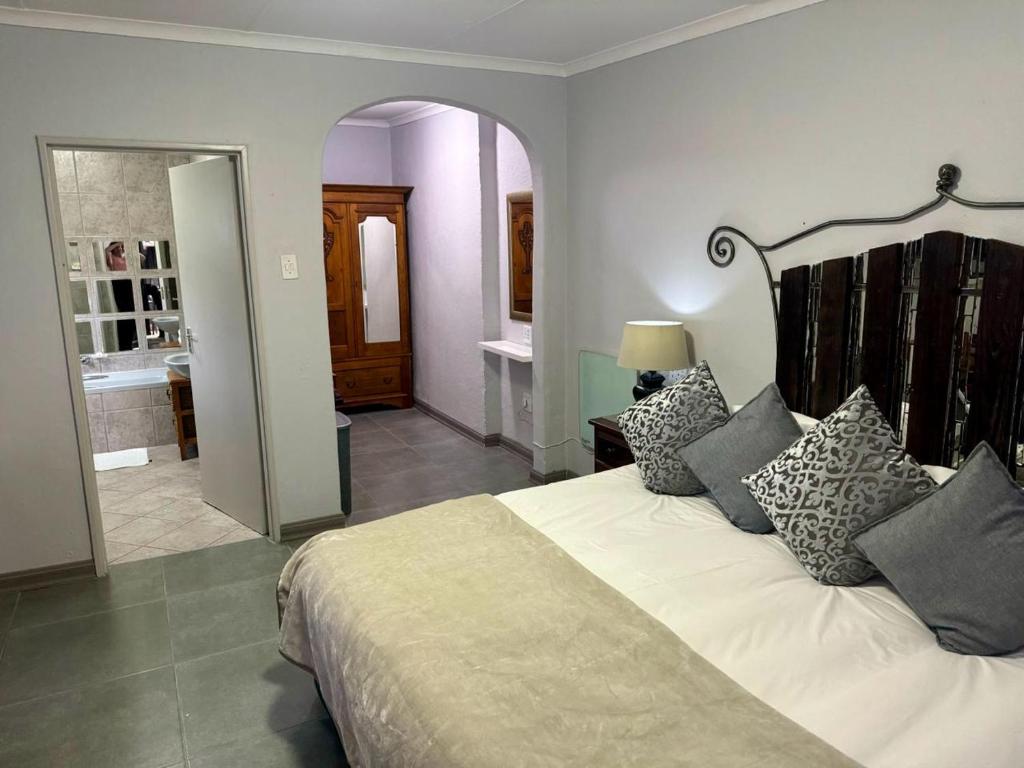 a bedroom with a large bed and a bathroom at Rabbit Hole Hotel in Krugersdorp