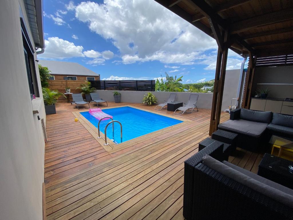 una terraza con piscina en la parte superior de una casa en Villa des Grenadelles en Saint-Paul