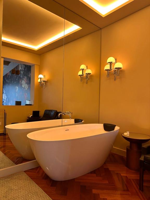 uma casa de banho com uma banheira e um espelho grande em The Felix 10 em Lisboa