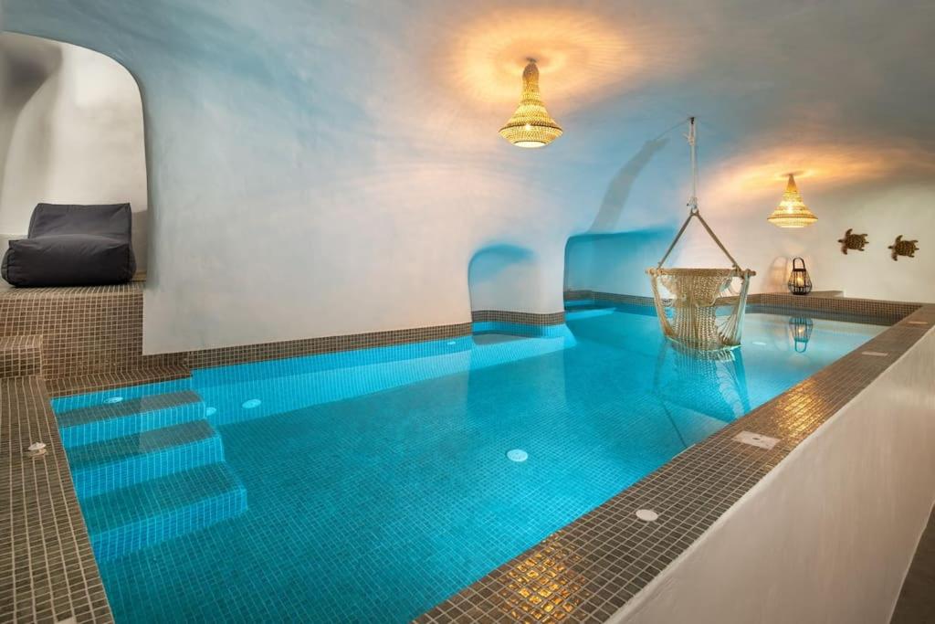 - une piscine d'eau bleue dans un bâtiment dans l'établissement Mystagoge Retreat cave with an indoor pool and gym, à Vóthon