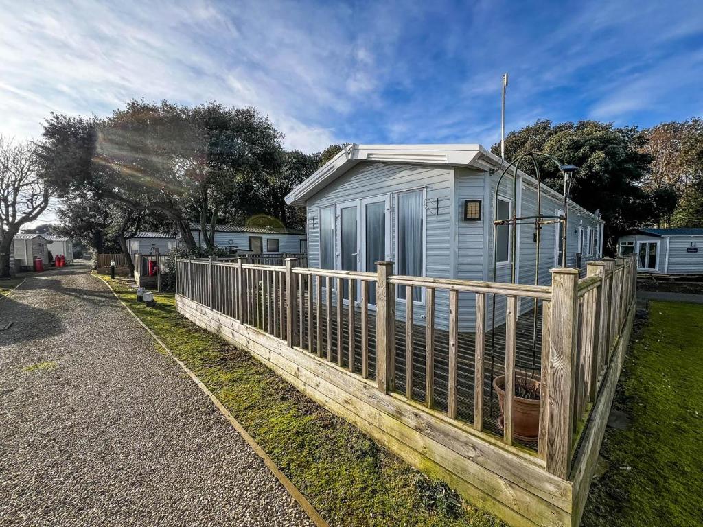 a tiny house behind a wooden fence at Beautiful Caravan With Decking At Azure Seas Ref 32060az in Lowestoft