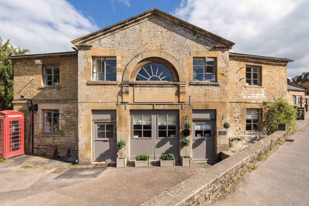 a brick house with a red phone booth in front of it at Classic Cotswolds Apartment, The Little Coach House in Blockley