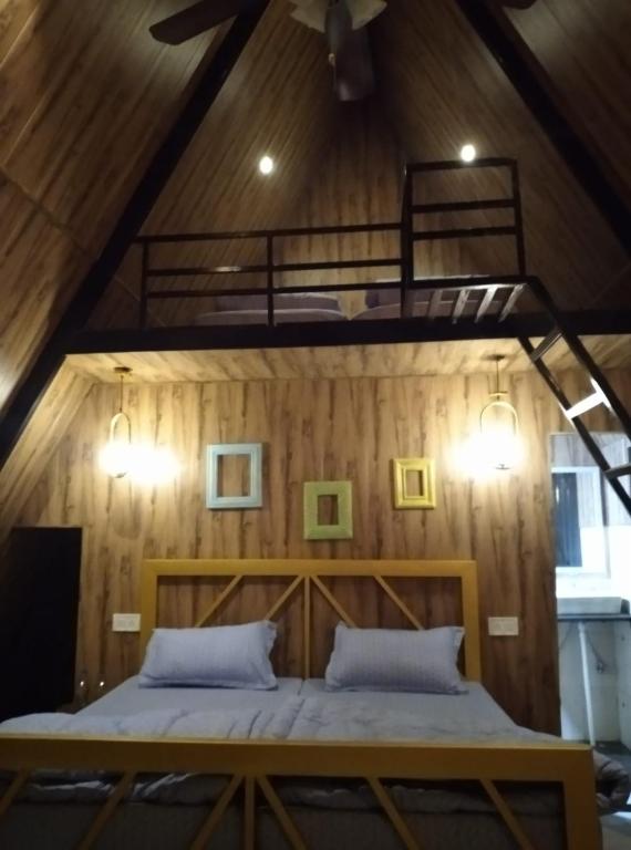 a bed in a room with a wooden wall at Camp O Royale in Dhanaulti