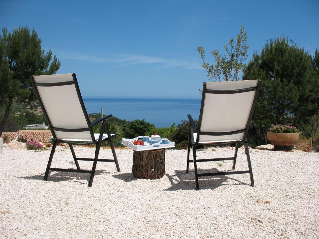 zwei Stühle neben einem Baumstumpf mit einem Tisch in der Unterkunft Agave Scopello in Scopello